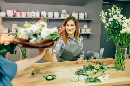 花店给女顾客送鲜花。背景花卉店内饰