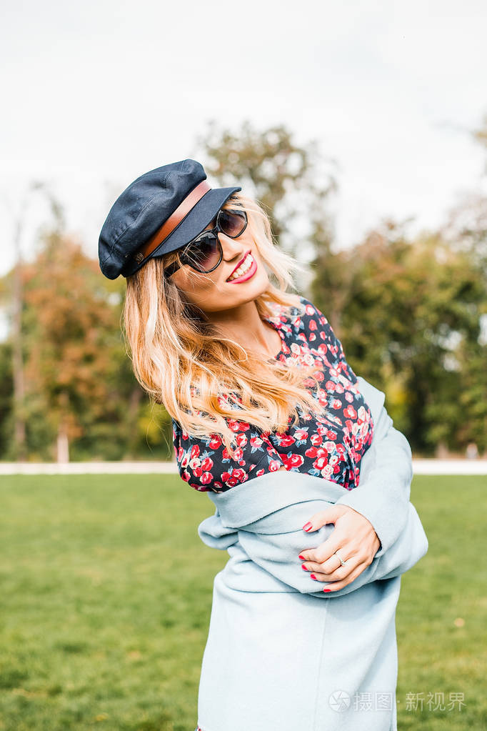 迷人的金发女郎戴着墨镜在公园里摆姿势