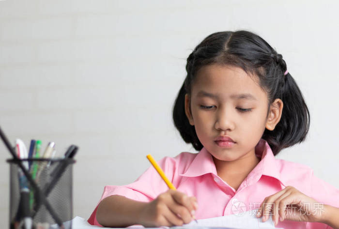 小女孩正在专心做作业.孩子们用黄色的铅笔写笔记本.