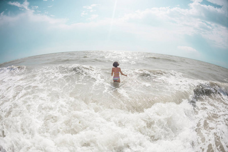 这个女孩走进海水。沐浴在海洋中的女人。在海岸上休息