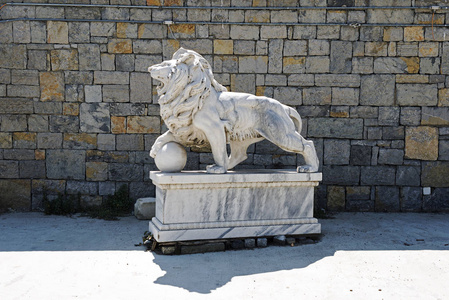 在伊斯坦布尔的一座石墙上, 一个剩余的狮子雕塑在停车场