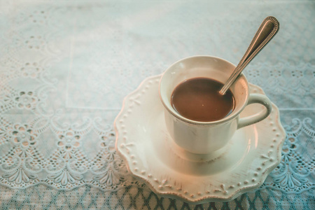 带热咖啡的白杯子和早晨的休息时间在一个漂亮的图案布的桌子上