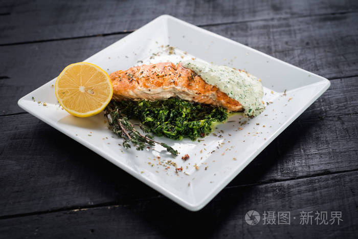 美味的鱼牛排配酱和香草在木质背景下