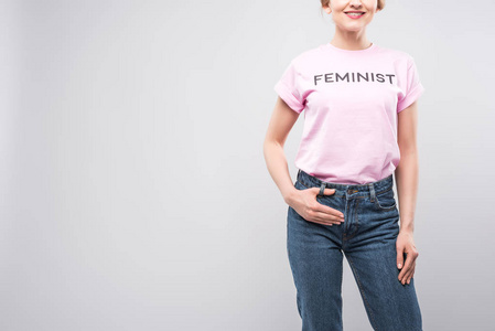 在粉红色女权主义的 t恤, 在灰色孤立的微笑妇女的裁剪视图