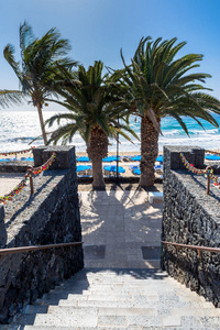 西班牙的波多黎各卡门2016年12月29日 在西班牙的卡门海滩上, 有棕榈和沙滩的海滨长廊。卡门是兰萨罗特岛上的主要旅游城
