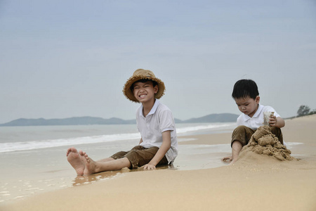 两个亚洲男孩在沙滩上玩沙子
