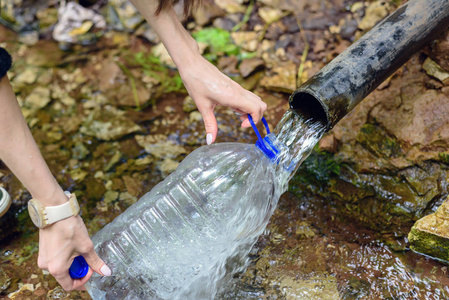用塑料瓶特写男人的手, 从泉水里填满干净的淡水, 地下的水源
