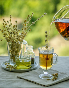 草药山茶从茶壶倒入玻璃图片