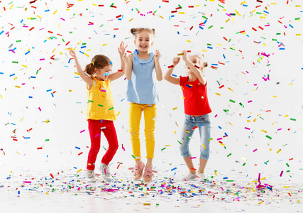 快乐的孩子在假日有乐趣和跳跃在多彩多姿的五彩纸屑在白色背景