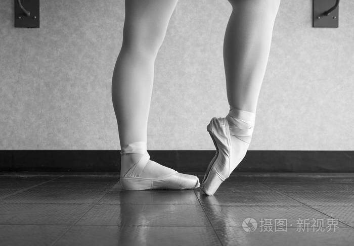 黑白版芭蕾舞演员在芭蕾课上用她的足尖鞋热身她的脚