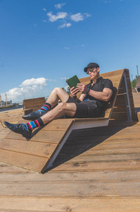 欧洲人, 一个穿黑衬衣的学生, 一顶在城市公园里看书的帽子, 靠近河边。
