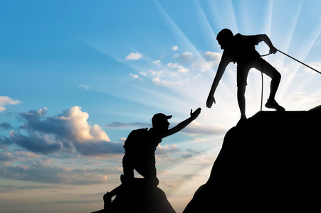 障碍之主一个男性登山者伸出援助之手, 以克服障碍的剪影.