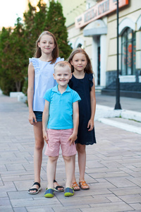 金发碧眼的小男孩和三岁的堂兄弟姐妹, 在夏日的街道上相遇