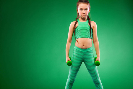 男孩女孩做健身运动与哑铃在绿色背景