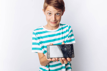 一个美丽的和情感的男孩的肖像, 在谁的手坏电话显示惊喜, 白色背景, 蓝色 t恤衫