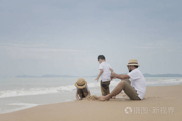 亚洲父亲在阴沉的日子里和儿子一起在沙滩上玩耍