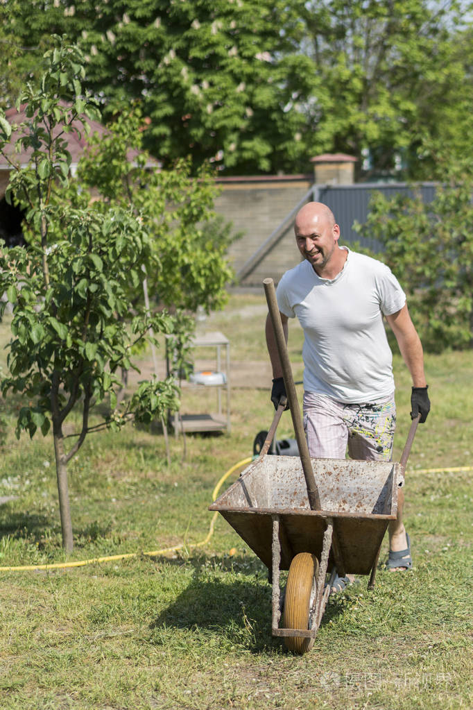 男人推手推车年轻人推着手推车在农场上