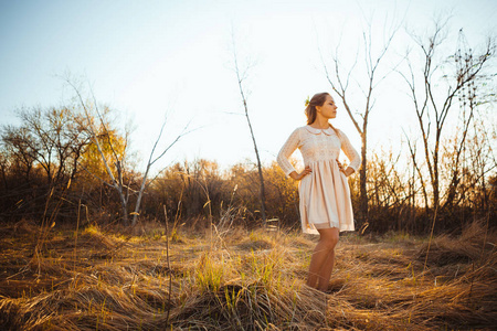 美丽的女孩站在田野上日落背景