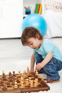 蹒跚学步男孩玩棋盘上的棋子