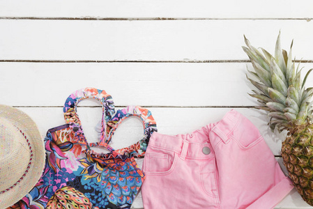 草帽, 热带印花泳装, 粉红色牛仔裤短裤, 菠萝。白色老木背景