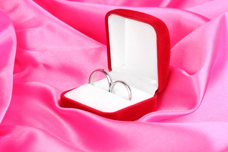 在红色框粉色布背景上的结婚戒指