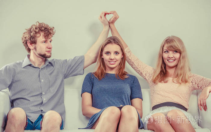 快乐的年轻人坐在沙发上男人和女人隐藏他们的爱作弊与她的女朋友的男