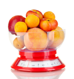 成熟的水果在厨房秤上白色隔离