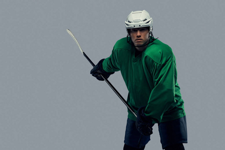 职业冰球运动员训练在充分的设备与游戏棍子。在灰色背景上隔离