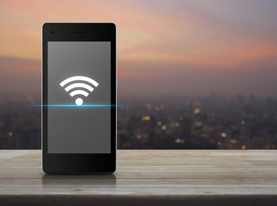 现代智能手机屏幕上的 wifi 连接图标在暖光日落技术和互联网概念上的城市景观模糊