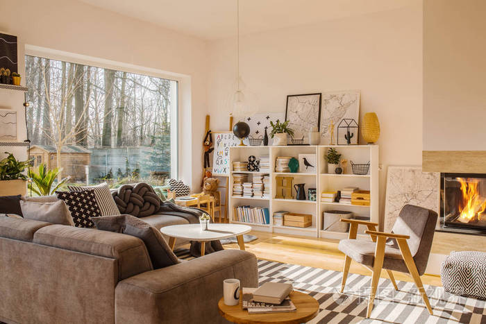 灰色木扶手椅靠近沙发在温暖的客厅内壁炉和窗口