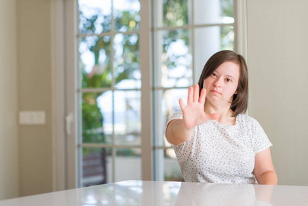 唐氏综合症妇女在家用张开手做停止标志以严肃和自信的表达, 防御手势