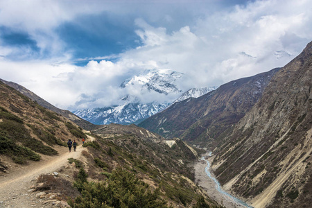 在喜马拉雅山上美丽的小径上的游客。云中的雪山山峰, 尼泊尔