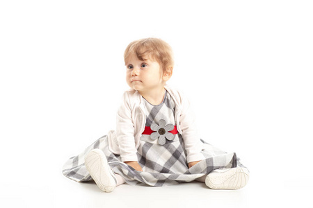 优雅快乐的女婴1岁坐在演播室地板上。白色背景。概念幸福