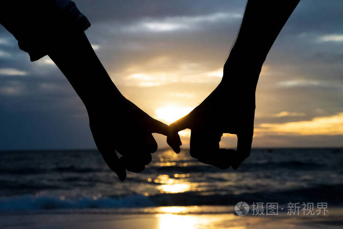 剪影夫妇人和妇女手一起举行在海和天空背景在日落期间为友谊天, 爱和