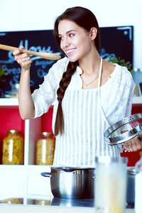 厨房里用木勺做饭的女人。烹调妇女