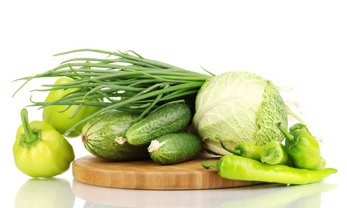 在菜板上白色隔离的新鲜绿色蔬菜