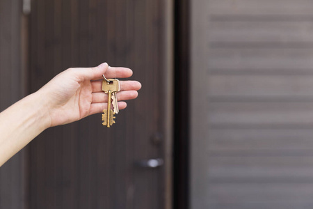 房间钥匙剪影房子钥匙在妇女的手在前门前面.