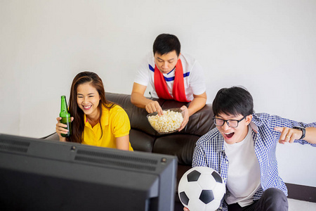 人们看足球。亚洲足球球迷在家里观看足球比赛快乐的情绪