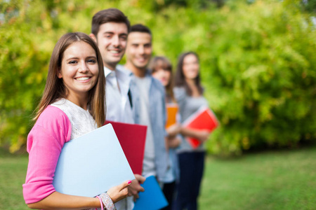 一群学生面前一个微笑的年轻学生的户外肖像