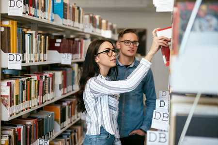 在大学图书馆学习的学生。男人和女人在书架上搜索书籍。高分辨率