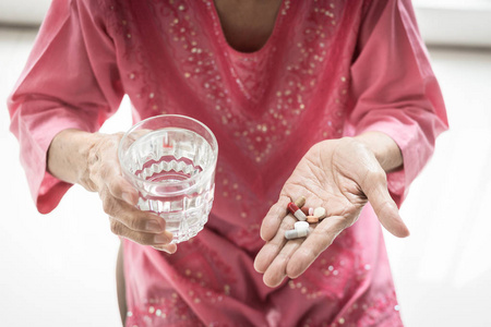 亚洲老年妇女正在服用和吃的药物和维生素帮助生病和健康的家庭, 医疗保健概念