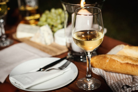 浪漫晚餐与一杯酒, 一条面包和小吃在一个老木桌上的一个夏日傍晚