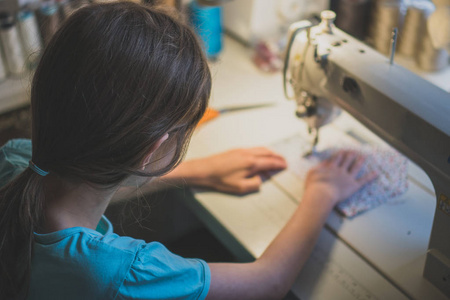 小女孩在缝纫机在家里工作。特写视图