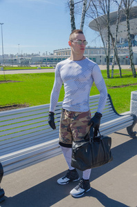 一个强壮的男人穿着白色运动制服, 戴着手套, 夏天在街上包着一个袋子。