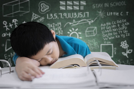 亚洲青春期学生的形象看起来很累后, 在教室里, 黑板上的涂鸦照片