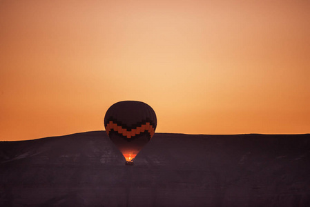 黎明时在山的背景下飞行的气球