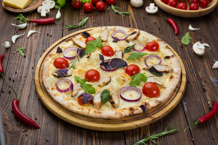 意大利比萨与鸡肉, 樱桃西红柿, 奶酪和洋葱板上装饰的叶子芝麻和罗勒