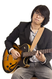 亚洲青年音乐家演奏吉他在白色背景上孤立