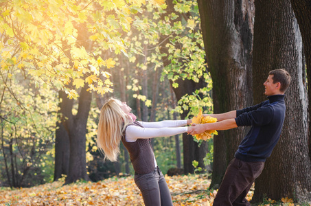 爱的情侣玩得很开心。在秋季公园散步。青年休闲