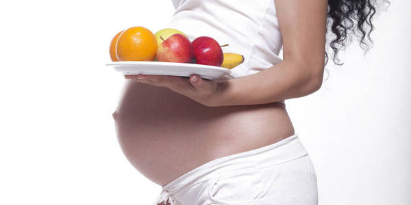 怀孕妇女拿着一个盘子与果子, 演播室隔绝了